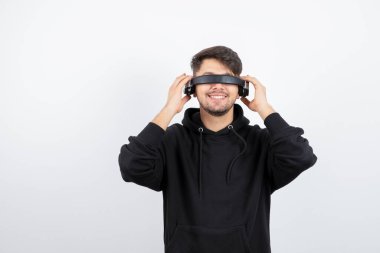Siyah kapüşonlu yakışıklı genç adam büyük kablosuz müzik kulaklıkları takıyor. Yüksek kalite fotoğraf
