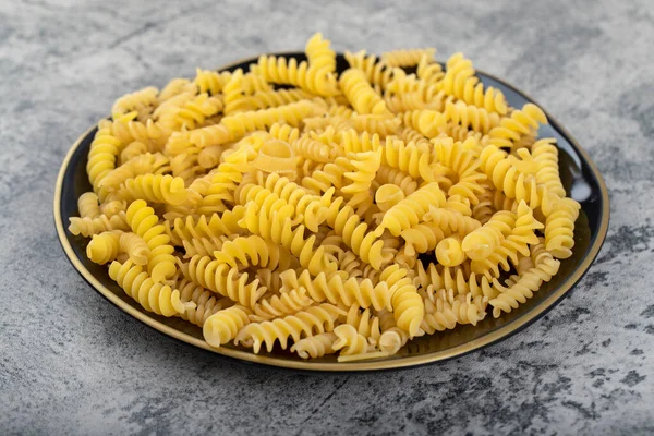 Schwarzer Teller Mit Rohen Fusilli Nudeln Auf Einem Steintisch Hochwertiges — Stockfoto