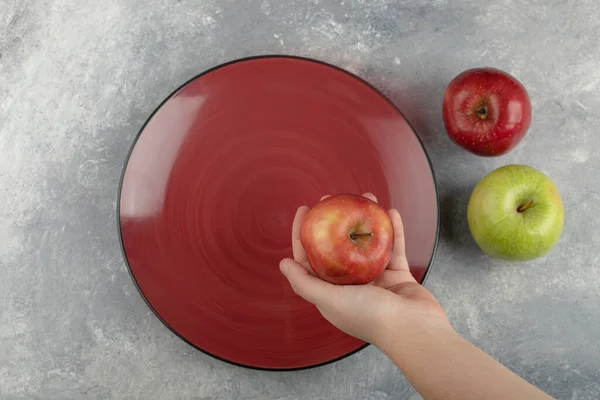 Male Hand Holding Fresh Red Apple Top Empty Red Plate — Stock Photo, Image