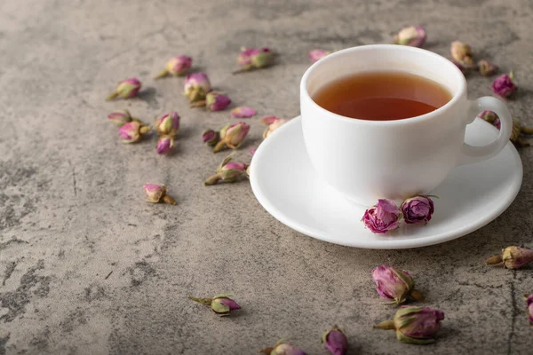 Cup of black hot tea with dried roses on stone surface. High quality photo