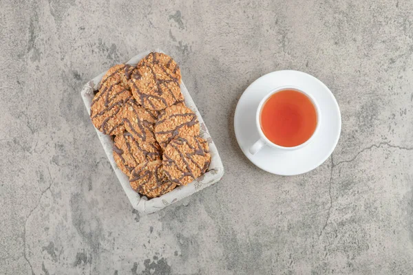 Sepette çikolata jöleli leziz çoklu tahıllı kurabiyeler ve bir fincan çay. Yüksek kalite fotoğraf