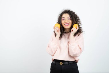 Portakal tutan pembe kazaklı genç kıvırcık kadın portresi. Yüksek kalite fotoğraf