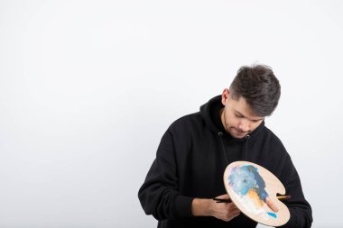 Elinde fırça tutan ve paletten renk seçen genç, yakışıklı bir sanatçı. Yüksek kalite fotoğraf