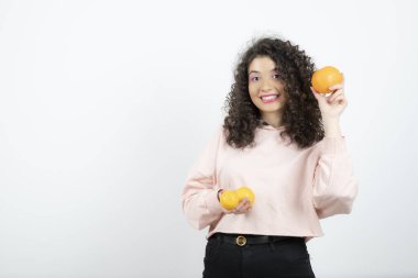 Portakal tutan pembe kazaklı genç kıvırcık kadın portresi. Yüksek kalite fotoğraf