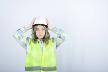 Beyaz fonda duran beyaz şapkalı genç inşaat işçisinin görüntüsü. Yüksek kalite fotoğraf