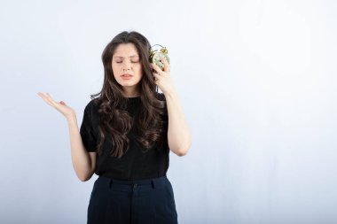 Beyaz arka planda uyuyan çalar saati olan genç bir kız resmi. Yüksek kalite fotoğraf