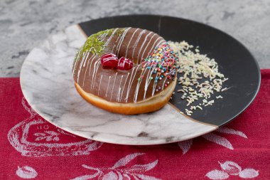 Kirazlı ve renkli şekerli bir tabak lezzetli çikolatalı çörek. Yüksek kalite fotoğraf