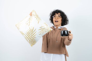 Yastık tutan ve kahve içen genç bir kadın resmi. Yüksek kalite fotoğraf