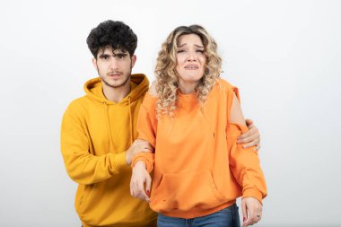 Beyaz duvarın üzerinde duran genç ve çekici bir çiftin portresi. Yüksek kalite fotoğraf