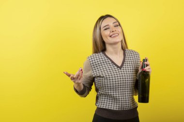 Elinde şarap şişesi olan ve ayakta duran genç bir kadın resmi. Yüksek kalite fotoğraf