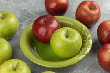 Yeşil kasede mermer zemin üzerinde taze kırmızı ve yeşil elmalar. Yüksek kalite fotoğraf