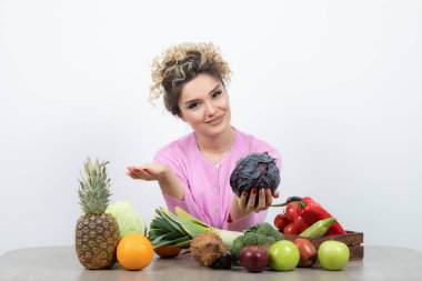 Masada elinde mor lahanayla oturan güzel bir ev hanımı resmi. Yüksek kalite fotoğraf