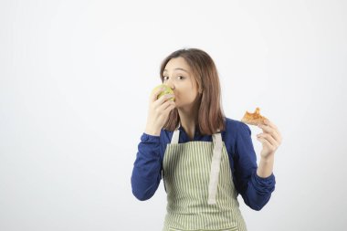 Önlüklü sevimli genç kız pizza yerine yeşil elma yiyor. Yüksek kalite fotoğraf