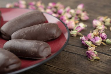 Kırmızı tabakta çikolatalı kekler ve ahşap arka planda güller. Yüksek kalite fotoğraf