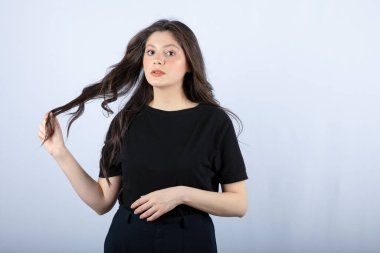 Siyah bluzlu esmer bir kızın beyaz duvardan kameraya baktığı görüntü. Yüksek kalite fotoğraf