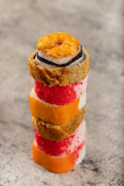 Stack of various sushi rolls placed on stone background. High quality photo