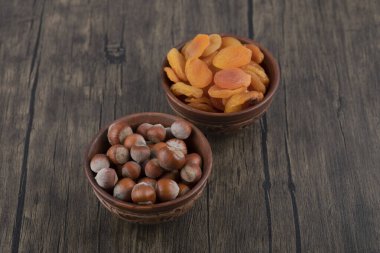 Tahta masada kurutulmuş kayısı meyveleri ve sağlıklı fındıklarla dolu tahta kaseler. Yüksek kalite fotoğraf