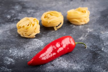 Mermer yüzeyinde kırmızı biberli çiğ makarna yuvaları. Yüksek kalite fotoğraf