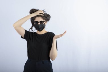 Beyaz arka plandaki salgın nedeniyle genç bir kızın portresi siyah bir maske takıyor. Yüksek kalite fotoğraf