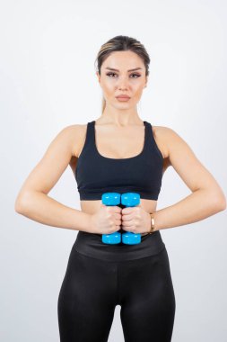 Siyah elbiseli sarışın kadın ayakta duruyor ve dambıllarıyla egzersiz yapıyor. Yüksek kalite fotoğraf