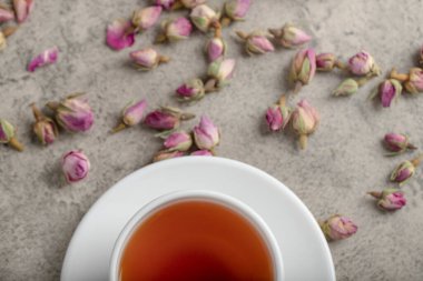 Taş yüzeyinde kurumuş güller olan bir fincan siyah çay. Yüksek kalite fotoğraf