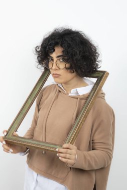 Gözlüklü genç bir kadın kafasını ahşap çerçevenin ortasında tutuyor. Yüksek kalite fotoğraf