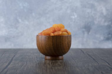 Ahşap bir masada sağlıklı kurutulmuş kayısı meyveleriyle dolu bir kase. Yüksek kalite fotoğraf