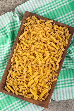 Taş zeminde ahşap bir kutu çiğ fusilli makarna. Yüksek kalite fotoğraf
