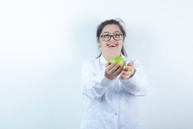 Elinde yeşil elma tutan doktor üniformalı genç bir kız. Yüksek kalite fotoğraf