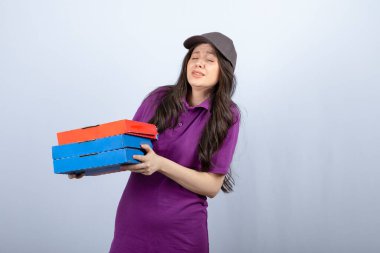 Mor üniformalı güzel teslimatçı kadın pizza kutularını tutmaya çalışıyor. Yüksek kalite fotoğraf