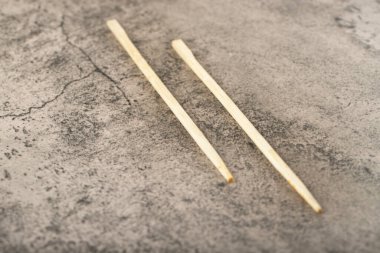 Disposable beech wooden chopsticks placed on stone background. High quality photo