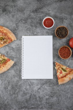 Lezzetli peynirli pizza dilimleri, baharatlar ve arka planda boş kağıt. Yüksek kalite fotoğraf