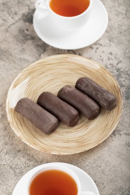 Taştan arka planda siyah çay bardakları olan bir tabak çikolata. Yüksek kalite fotoğraf