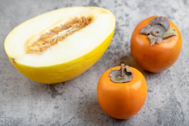 Yarım dilimlenmiş sarı kavun ve taş zeminde olgun hurma. Yüksek kalite fotoğraf