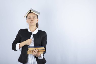 Kafasında bir sürü kitap olan güzel bir öğretmenin resmi. Yüksek kalite fotoğraf