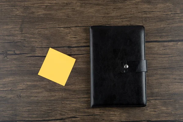 Ahşap arka planda not defteri olan sarı kare çıkartma. Yüksek kalite fotoğraf