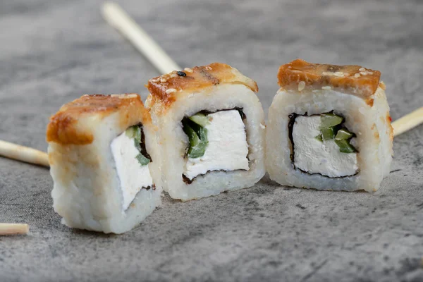 Unagi sushi Philadelphia rolls with wooden disposable chopsticks placed on a stone background . High quality photo