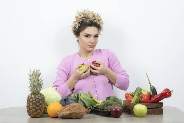 Kręcone Kobieta Siedzi Przy Stole Trzymając Pyszne Owoce Wysokiej Jakości — Zdjęcie stockowe