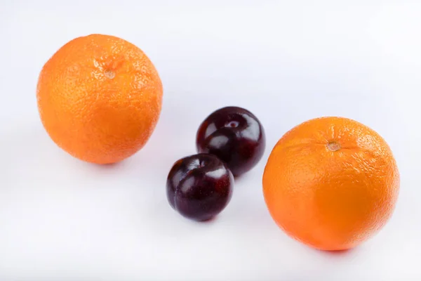 美味多汁的紫色李子 白色背景上有新鲜的橙子 高质量的照片 — 图库照片