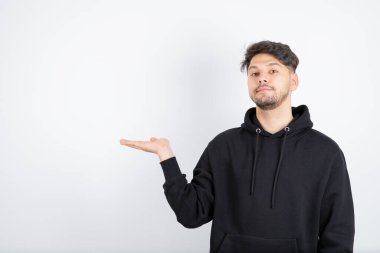 Siyah kazaklı genç adam portresi ayakta ve açık alan tutuyor. Yüksek kalite fotoğraf