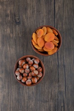 Tahta masada kurutulmuş kayısı meyveleri ve sağlıklı fındıklarla dolu tahta kaseler. Yüksek kalite fotoğraf