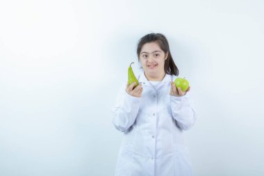 Doktor üniformalı genç bir kız elinde yeşil elmalı armut meyvesi tutuyor. Yüksek kalite fotoğraf