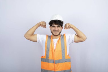 Beyaz kasklı yakışıklı genç adam beyaz duvarın üzerinde kameraya poz veriyor. Yüksek kalite fotoğraf