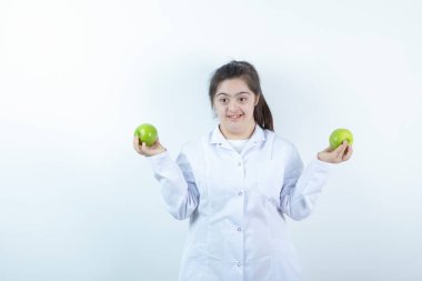 Doktor üniformalı genç bir kız elinde yeşil elma meyveleri tutuyor. Yüksek kalite fotoğraf