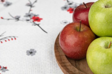 Tahta tabağa yerleştirilmiş kırmızı ve yeşil taze elma. Yüksek kalite fotoğraf