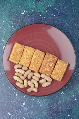 Sağlıklı fındıklı kırmızı bir tabak ve galaksi arka planında lezzetli krakerler. Yüksek kalite fotoğraf