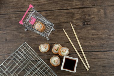 Soya soslu lezzetli suşi ruloları ve ahşap yüzeyde yemek çubukları. Yüksek kalite fotoğraf