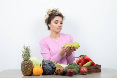 Güzel ev hanımının elinde taze elmalarla masada oturduğu bir fotoğraf. Yüksek kalite fotoğraf