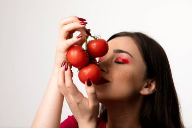 Güzel bir kız ellerinde bir avuç kırmızı domates kokluyor. Yüksek kalite fotoğraf