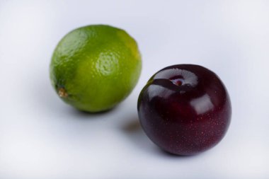 Taze yeşil limon ve mor erik beyaz arka planda izole edilmiş. Yüksek kalite fotoğraf